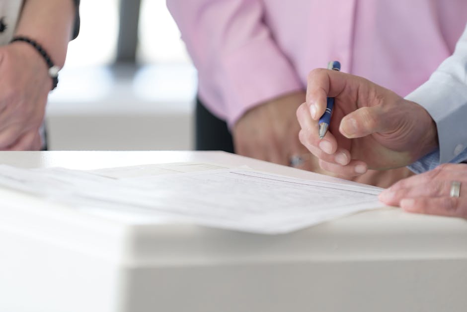 Close-up of hands signing documents in an office setting, emphasizing collaboration and decision-making.